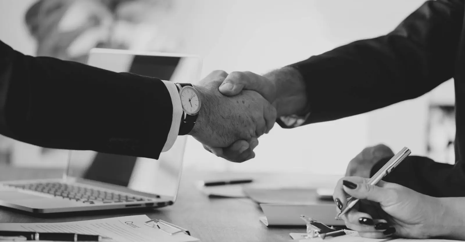 Two people shaking hands over a contract
